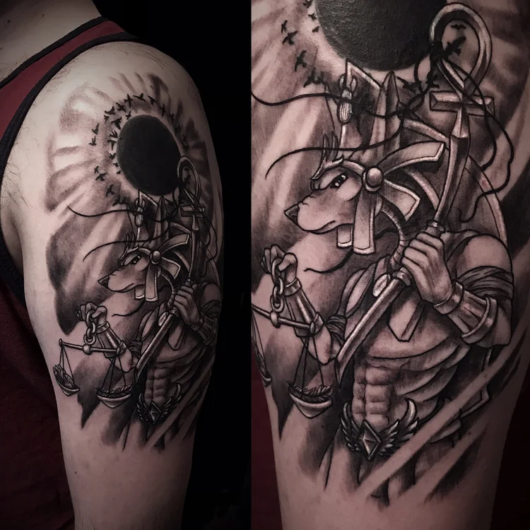 Black and grey sleeve with a sun, scales and a figure holding an anchor